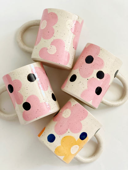 This handmade ceramic mug features a charming design of large dots over delicate flowers, perfect for any flower lover. Made with care and attention to detail, this mug is a beautiful addition to any kitchen. Enjoy your favorite beverage while admiring the intricate artistry of this unique piece. Crafted to bring joy and beauty to your daily routine.