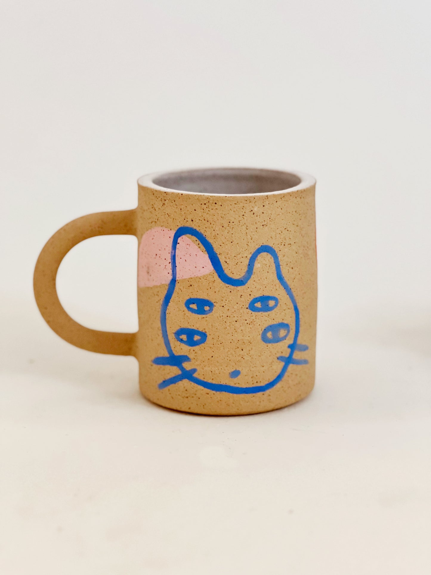 Introducing our Large Little Four Eyes Handmade Ceramic Mug, featuring our signature design inspired by our adorable and beloved pet, Bowl. This cute and unique mug is perfect for pet lovers. Handcrafted with care, it's the perfect addition to your morning routine. Brighten up your day with every sip!