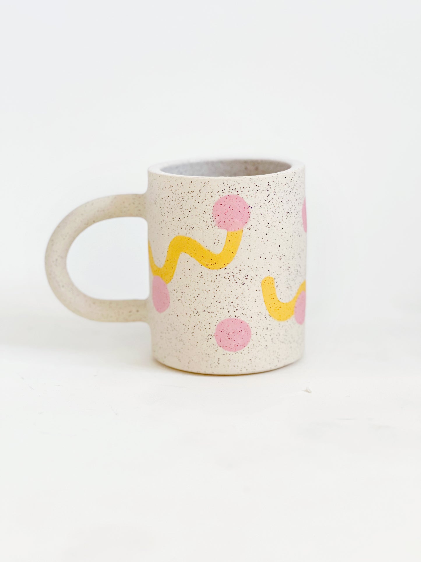 This handmade ceramic mug features playful polka dots over different shapes, adding a colorful and fun touch to your daily coffee or tea routine. Handcrafted with attention to detail, this unique mug is a must-have for any ceramic collection. Enjoy your favorite drink in a playful yet elegant way.