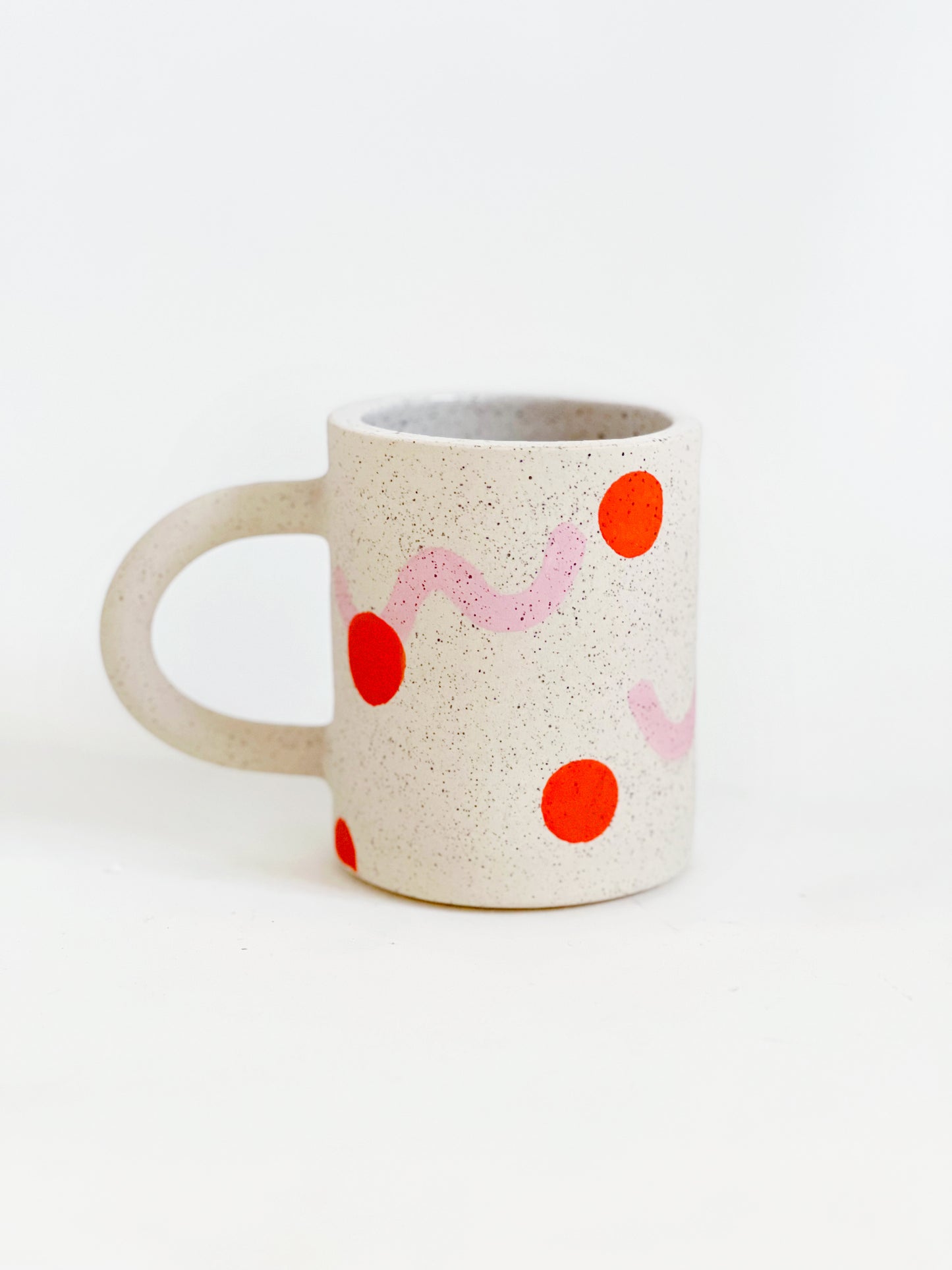 This handmade ceramic mug features playful polka dots over different shapes, adding a colorful and fun touch to your daily coffee or tea routine. Handcrafted with attention to detail, this unique mug is a must-have for any ceramic collection. Enjoy your favorite drink in a playful yet elegant way.