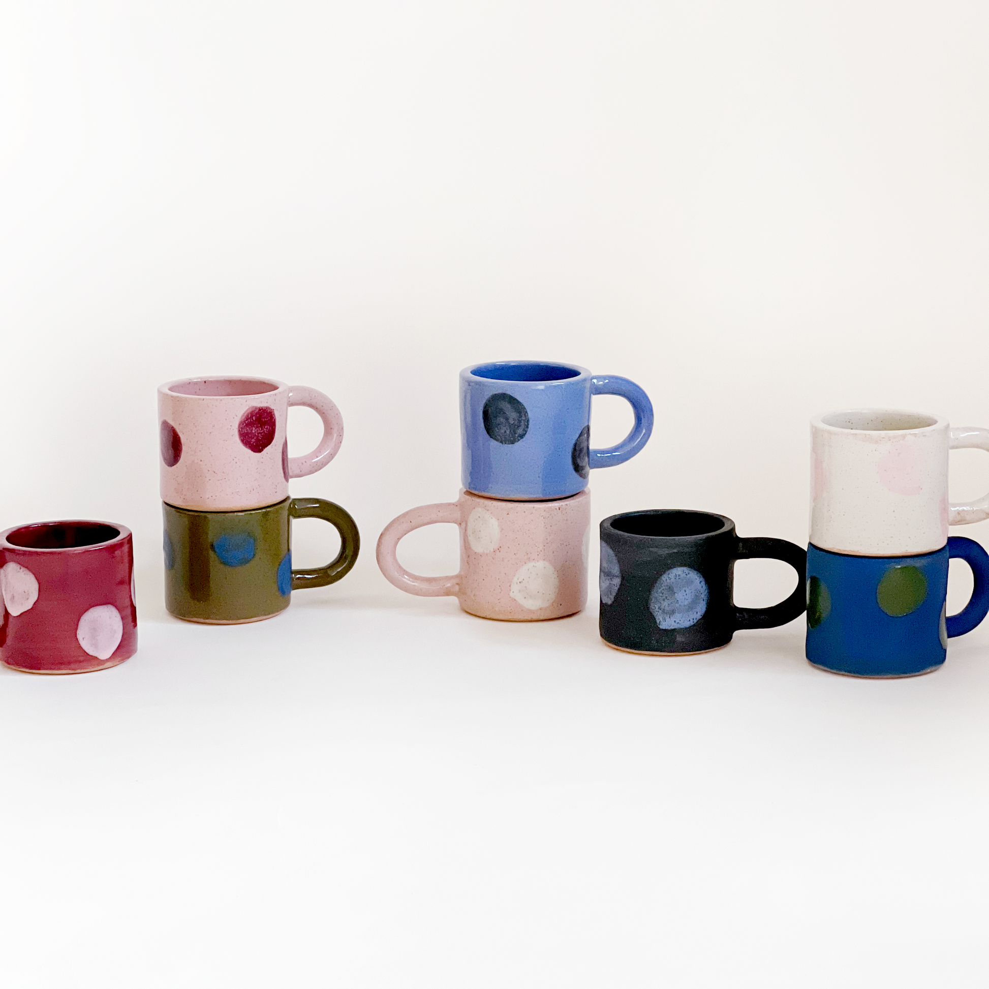 Set of colorful ceramic mugs with polka dot patterns on a white background