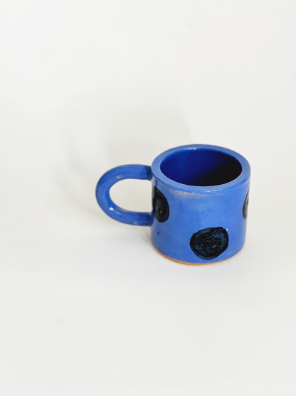 Blue ceramic mug with black spots on a white background
