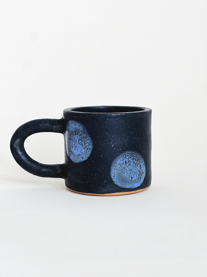 Pink speckled mug with red dots designs on a white background