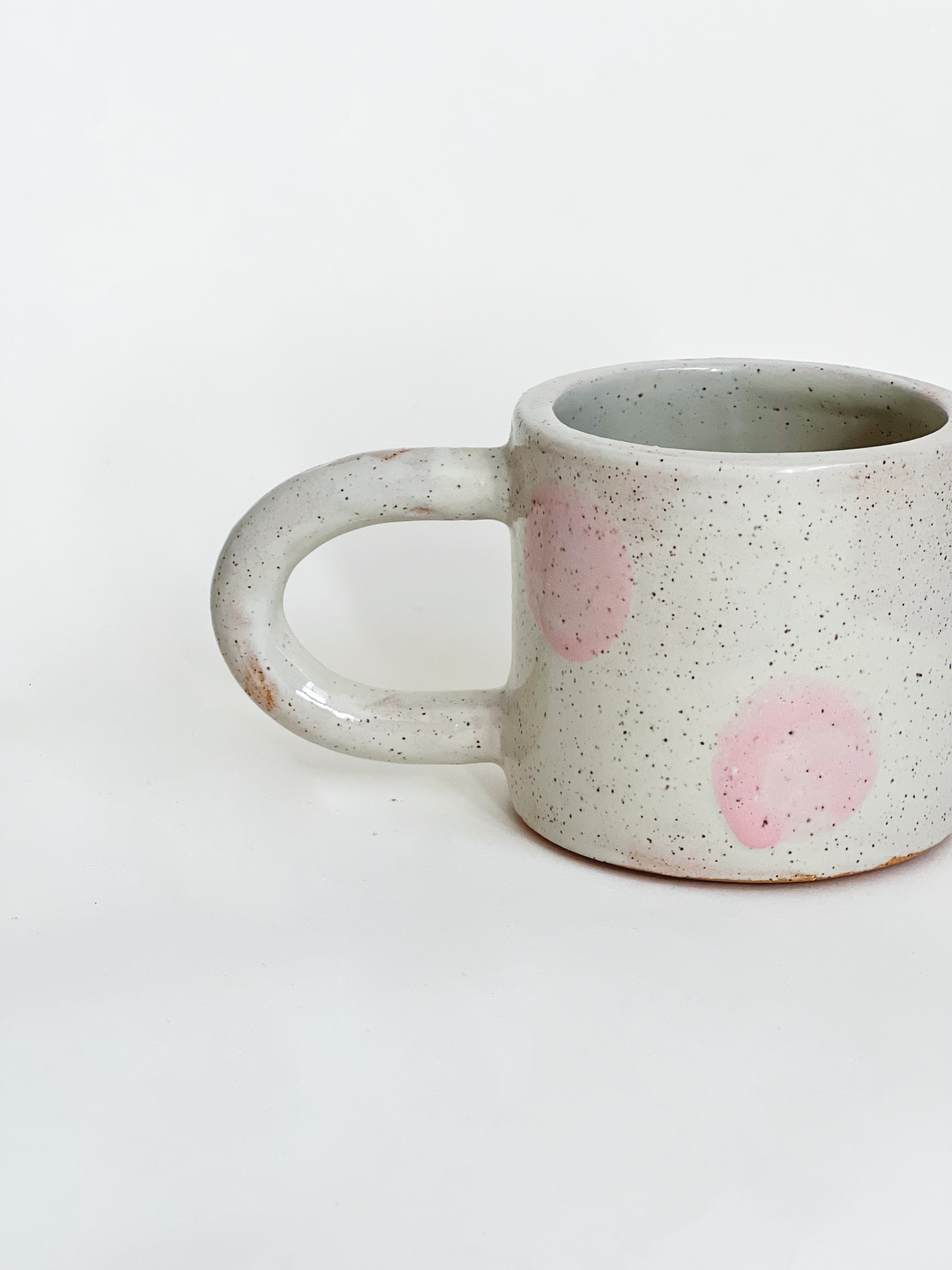 Speckled ceramic mug with pink dots on a white background