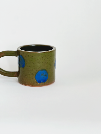 Green ceramic mug with blue circular patterns on a white background