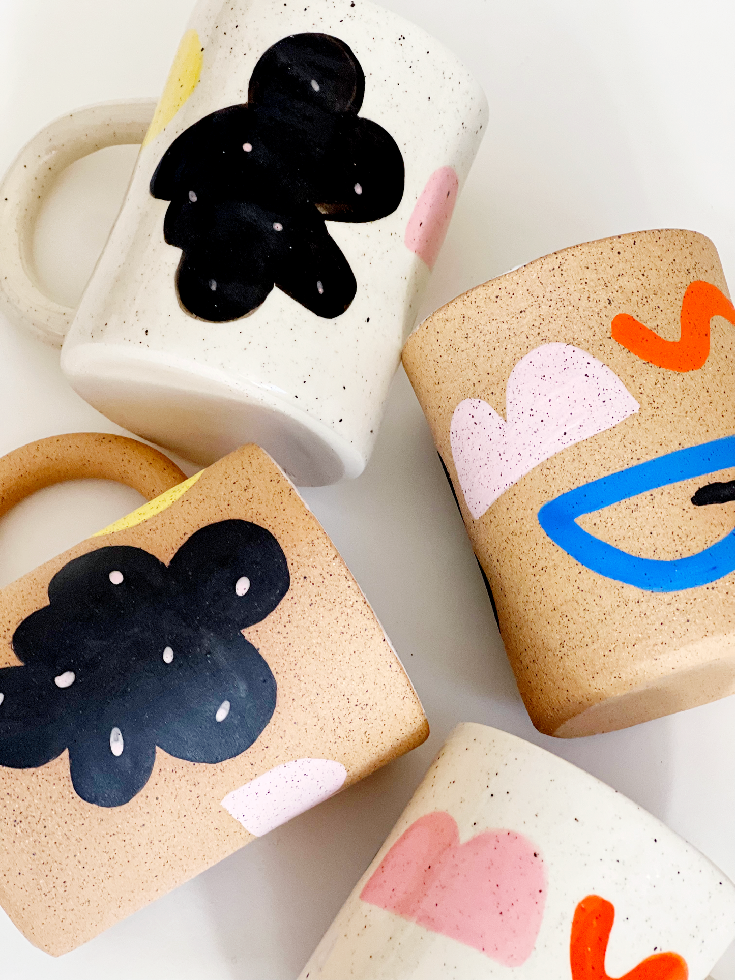 Four ceramic mugs with abstract designs on a white background
