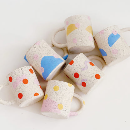 This handmade ceramic mug features playful polka dots over different shapes, adding a colorful and fun touch to your daily coffee or tea routine. Handcrafted with attention to detail, this unique mug is a must-have for any ceramic collection. Enjoy your favorite drink in a playful yet elegant way.