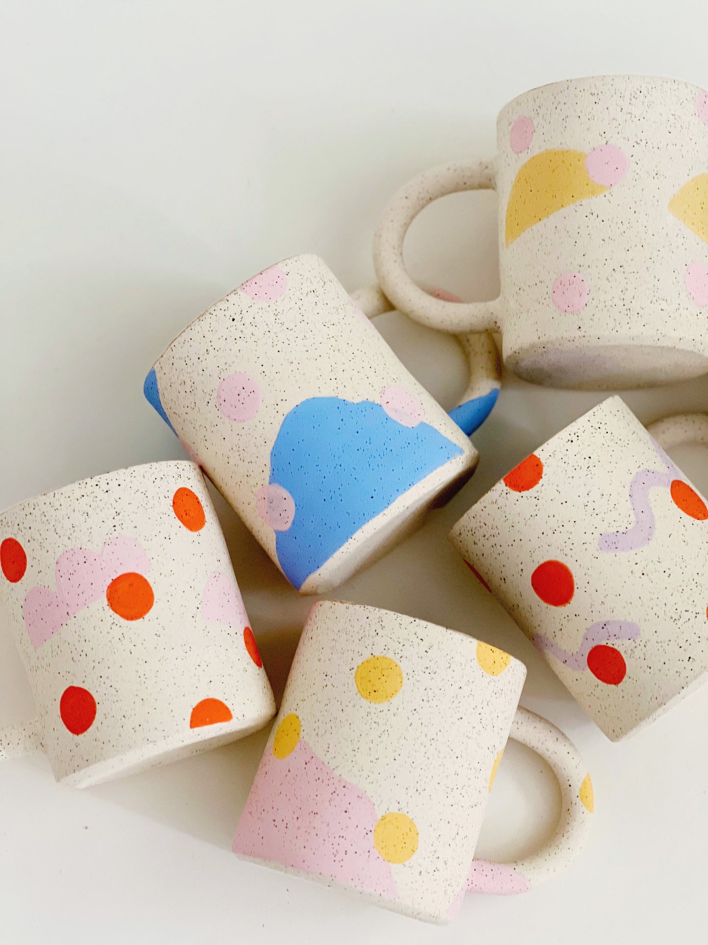 This handmade ceramic mug features playful polka dots over different shapes, adding a colorful and fun touch to your daily coffee or tea routine. Handcrafted with attention to detail, this unique mug is a must-have for any ceramic collection. Enjoy your favorite drink in a playful yet elegant way.