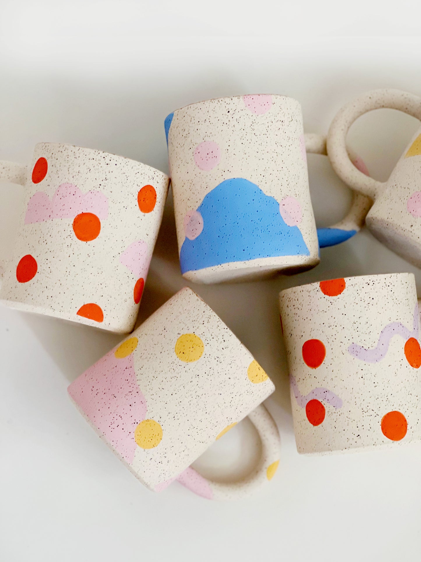 This handmade ceramic mug features playful polka dots over different shapes, adding a colorful and fun touch to your daily coffee or tea routine. Handcrafted with attention to detail, this unique mug is a must-have for any ceramic collection. Enjoy your favorite drink in a playful yet elegant way.