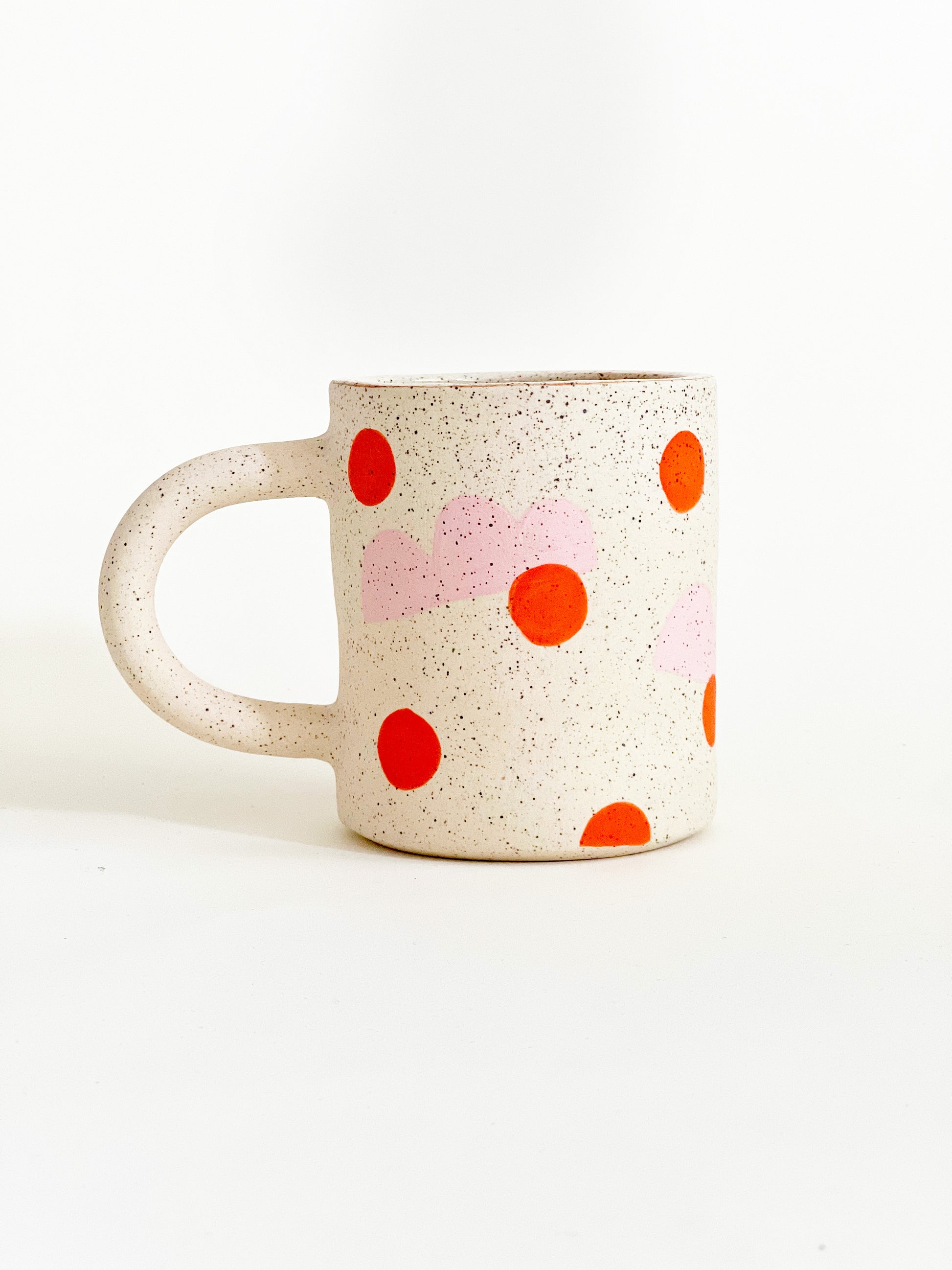 This handmade ceramic mug features playful polka dots over different shapes, adding a colorful and fun touch to your daily coffee or tea routine. Handcrafted with attention to detail, this unique mug is a must-have for any ceramic collection. Enjoy your favorite drink in a playful yet elegant way.