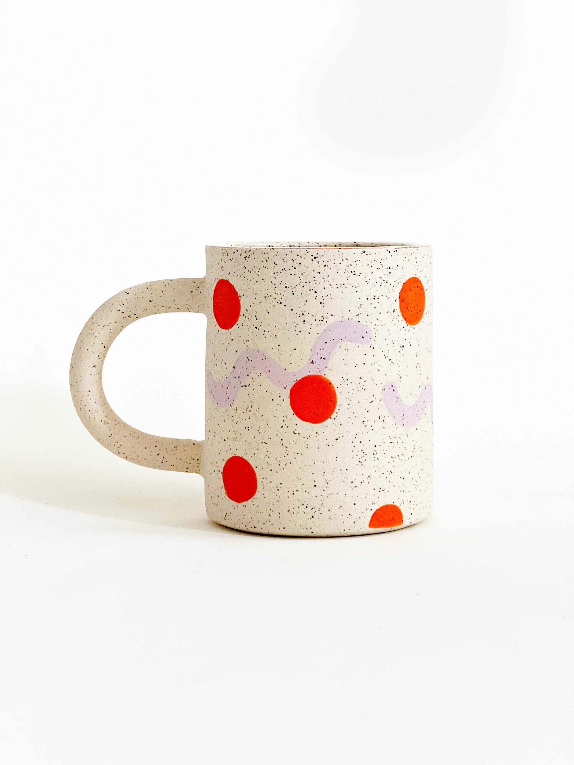 This handmade ceramic mug features playful polka dots over different shapes, adding a colorful and fun touch to your daily coffee or tea routine. Handcrafted with attention to detail, this unique mug is a must-have for any ceramic collection. Enjoy your favorite drink in a playful yet elegant way.