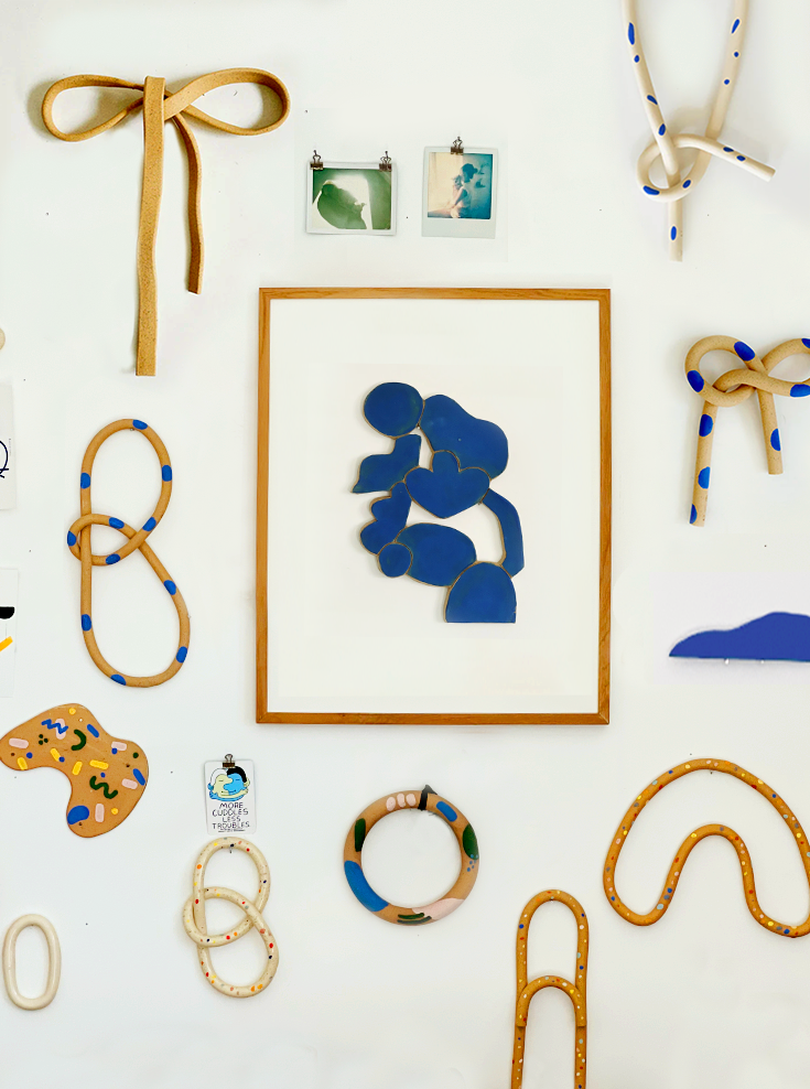 Decorative items including a blue abstract painting, ribbons, and paper clips on a white background.